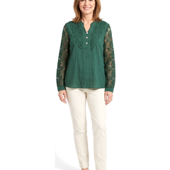 Woman wearing the green crochet lace blouse with cream trousers, standing front on