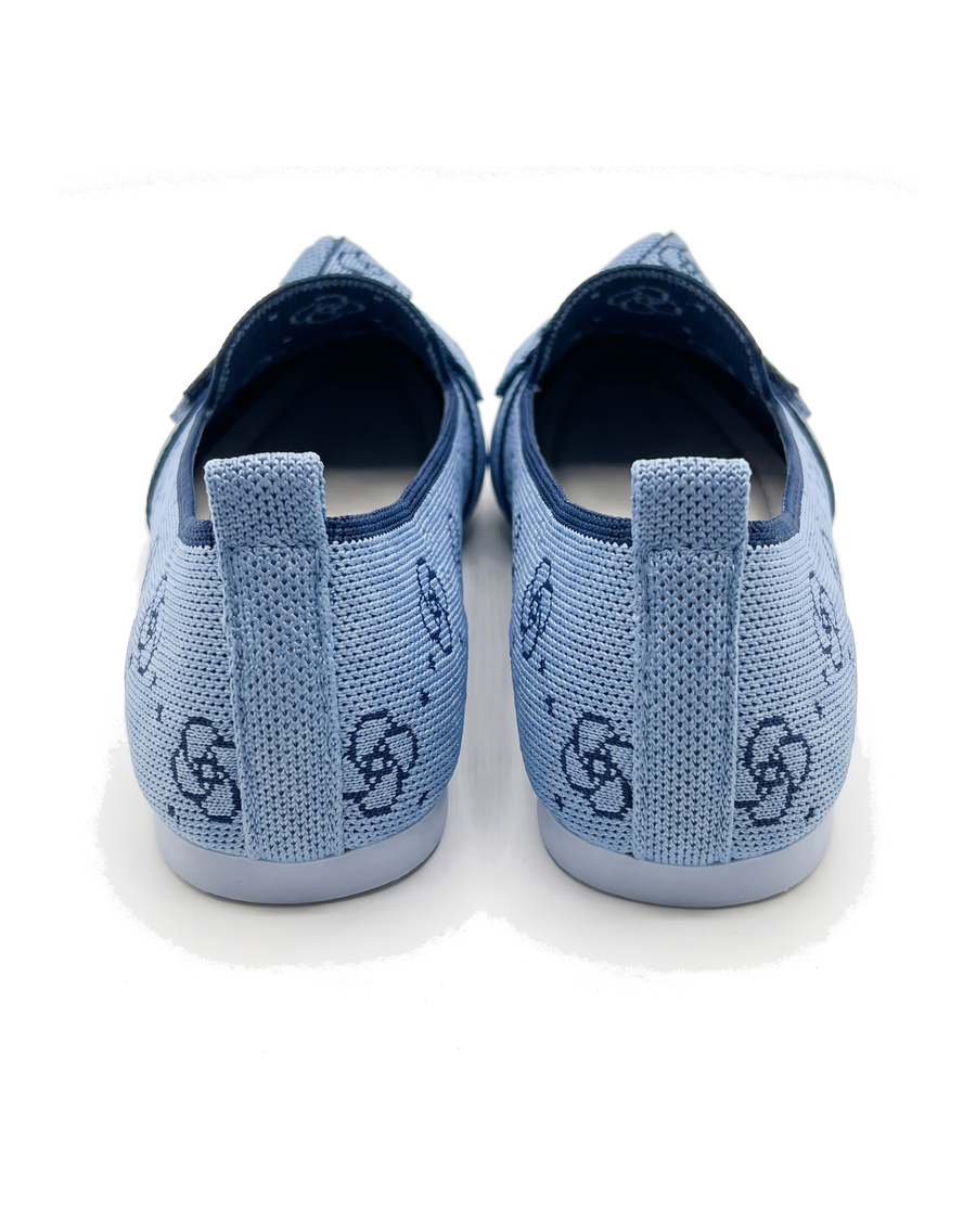 Light blue floral knit flats seen from the back with heel pull tabs on white background