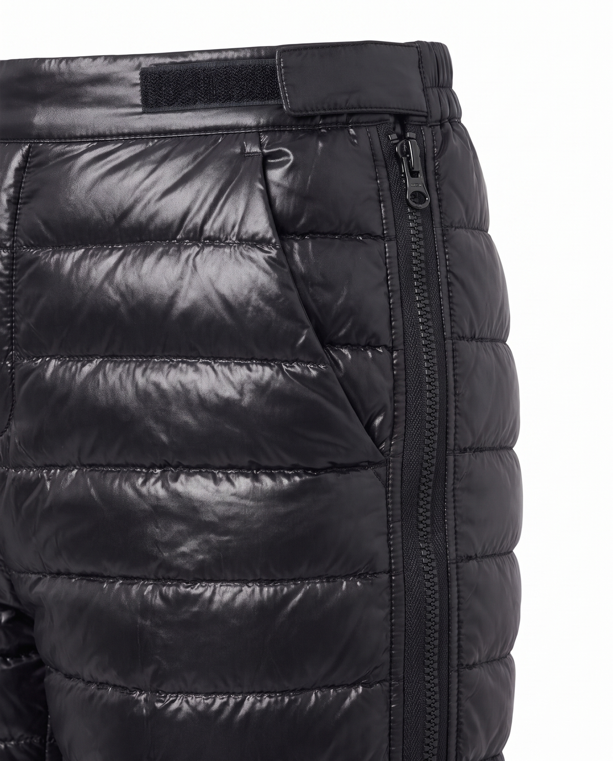 Close up detail of the glossy black quilted channels, velcro waist tab and full length side zip on the Aurora snow pants