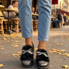 Black crystal bow platform loafers worn with cropped jeans on a city sidewalk in fall