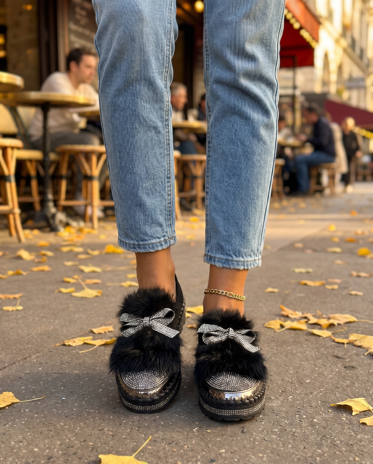 Black crystal bow platform loafers worn with cropped jeans on a city sidewalk in fall